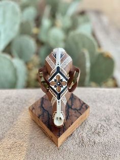 a wooden cross on top of a table next to some cacti and succulents