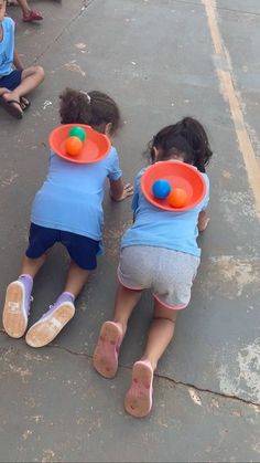 three children sitting on the ground playing with frisbees