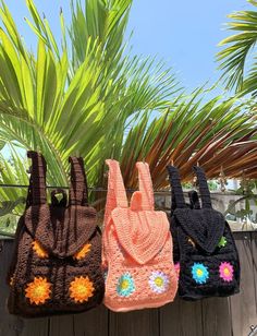 three crocheted purses hanging on a clothes line with palm trees in the background