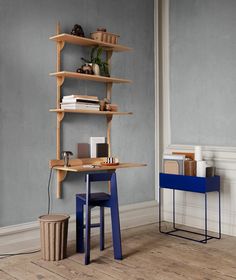 a wooden desk sitting next to a blue chair in a room with gray walls and wood flooring