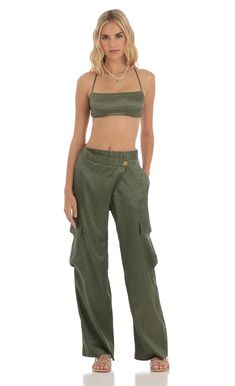 a woman standing in front of a white background wearing an army green crop top and cargo pants