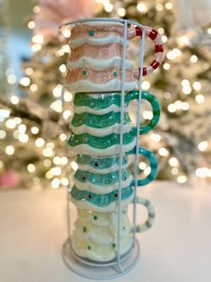 a stack of coffee mugs sitting on top of a table next to a christmas tree