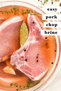 two raw pork chops sit in a bowl of broth with herbs on top