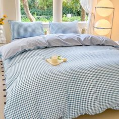 a blue and white checkered comforter set on a bed in a room with windows