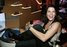 a woman sitting on top of a toilet in a room with shelves and other items