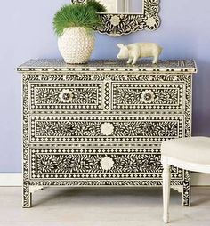 an ornate dresser and mirror in a blue room with white furniture on the floor next to it