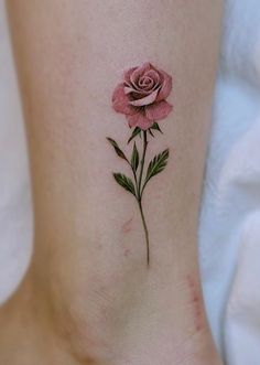 a small pink rose tattoo on the side of a woman's leg and foot