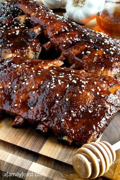 ribs covered in bbq sauce and sesame seeds on a cutting board next to garlic