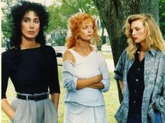 three women standing next to each other in front of a tree with their arms crossed