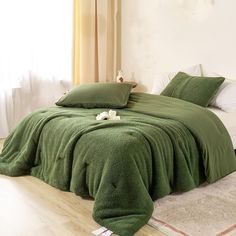 a bed covered in green blankets and pillows