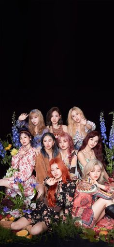 the group of girls are posing together in front of flowers