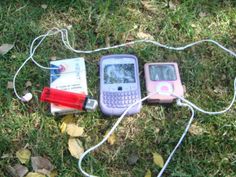 three cell phones are laying on the ground with wires attached to them and one is plugged in