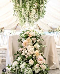 an arrangement of flowers and greenery on a table in a marquee at a wedding