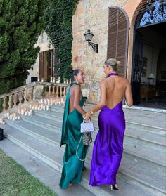 two women in dresses are standing on the steps talking to each other and holding hands