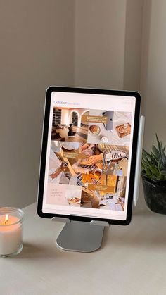 a desktop computer sitting on top of a desk next to a candle and potted plant