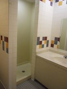 a bathroom with a sink, mirror and bathtub next to a tiled wall that has multicolored tiles on it