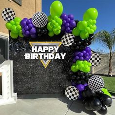 a happy birthday sign with balloons and checkers on it in front of a building