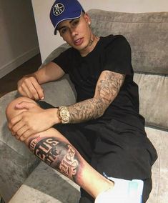 a man with tattoos sitting on a couch