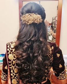 the back of a woman's head wearing a gold and maroon bridal hair piece