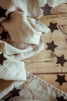 some black stars are laying on top of white linens and brown wood planks