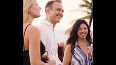 two women and a man standing next to each other with wine glasses in their hands