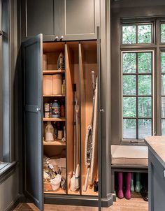 an open cabinet in a kitchen next to a window