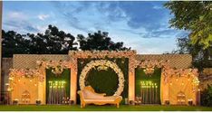 an outdoor wedding setup with white flowers and greenery on the wall, surrounded by lush green grass