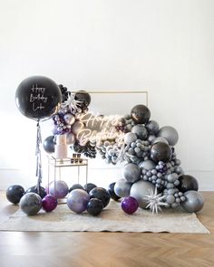 a table topped with balloons and other items on top of a wooden floor next to a mirror