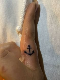 a person with a small tattoo on their left hand and an anchor in the middle