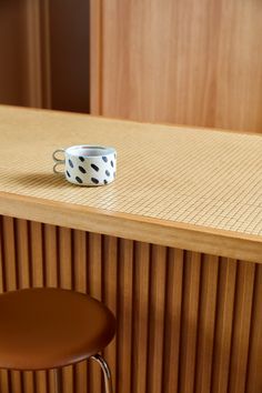 a polka dot coffee cup sitting on top of a wooden counter next to a bar stool