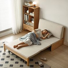 a woman laying on top of a bed next to a book shelf