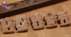 five pieces of carved clay sitting on top of a wooden table next to a ruler