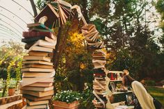 a tall stack of books sitting on top of a lush green park covered in trees