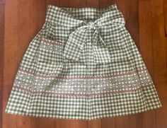 a green and white checkered skirt sitting on top of a wooden floor