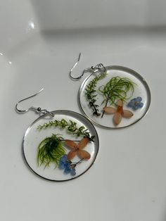 Gorgeous colorful wildflowers  with delicate ferns hand picked, pressed and dried for 2-3 days.   Once dried, I began the process of creating one of kind pieces which are preserved in a high quality non-toxic two part resin.  They are set in an open back hoop bezel, measuring 1-5/8 inch in diameter with silver earring wires. They are lightweight, beautiful and perfect for any occasion. ** Happy to answer any questions you may have, and invite you to share your thoughts on these special botanical earrings OR if you're interested in a custom or personalized version! Send me a message - I love connecting with customers! ** As in nature, there may be differences in shape, color or foraged elements.  Each item is unique therefore the piece you receive might not be exactly as shown in photos.  T Nature-inspired Round Pressed Flowers Earrings, Nature-inspired Dangle Earrings With Pressed Flowers, Botanical Flower Drop Earrings, Bohemian Pressed Flower Earrings, Delicate Pressed Flower Earrings, Bohemian Flower Earrings With Pressed Flowers, Delicate Round Earrings With Pressed Flowers, Botanical Drop Earrings With Pressed Flowers, Nature-inspired Flower Earrings With Birth Flower Detail