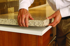 a man in white shirt and khaki pants standing next to counter with granite top