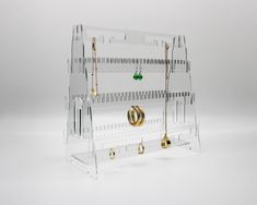 an acrylic jewelry rack with earrings hanging from it's sides, on a white background