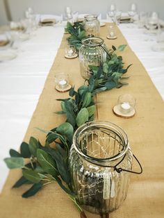 the table is set with candles and greenery