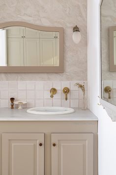 a white bathroom sink sitting under a mirror next to a wall mounted faucet