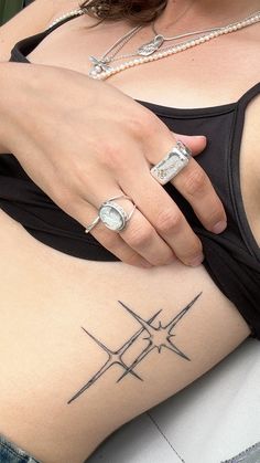 a woman with a tattoo on her stomach wearing a black tank top and silver rings