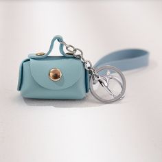 a small blue purse with a metal keychain attached to the front and side