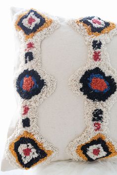 a white pillow with multicolored crocheted designs on the front and back