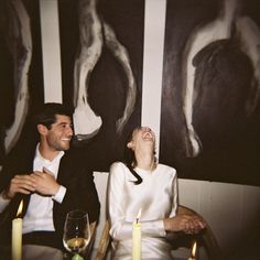 a man and woman sitting next to each other at a table with candles in front of them