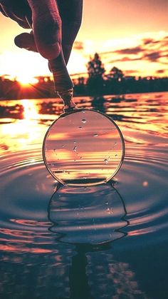 a person standing on top of a body of water with the sun setting in the background