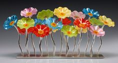 a group of multicolored flowers sitting on top of a metal stand next to each other