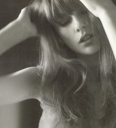 a black and white photo of a woman with her hair blowing in the wind,