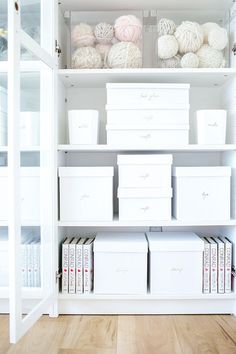 the shelves are filled with white boxes and crochet balls, books, and yarn