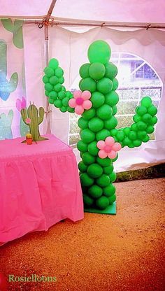 there is a large balloon cactus next to a table with a pink cloth on it