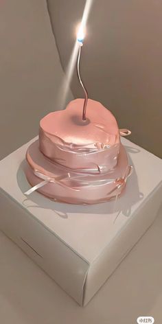 a pink cake sitting on top of a white box with a lit candle sticking out of it