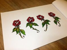 an open book with red roses drawn on the pages and some green leaves sticking out of it